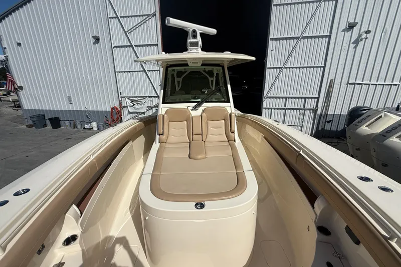 Slide: The Image of 2022 Scout 355 LXF boat with beige seating, docked near a large white building. - 34