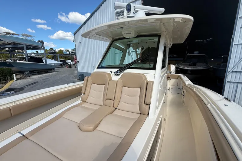 Slide: The Image of 2022 Scout 355 LXF boat with luxurious seating and sleek design in a marina setting. - 36