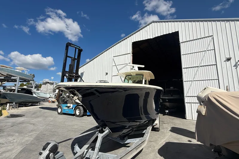 Slide: The Image of 2022 Scout 355 LXF boat outside a large white storage building under a blue sky. - 4