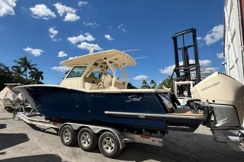 Slide: The Image of 2022 Scout 355 LXF boat on trailer, blue hull, Mercury engines, sunny day. - 5