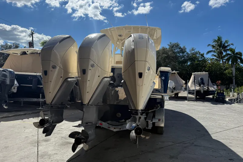 Slide: The Image of 2022 Scout 355 LXF boat with triple outboard engines in a sunny marina. - 7