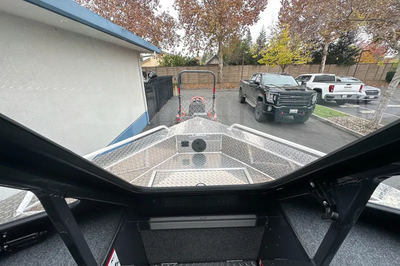 Slide: The Image of Interior view of 2026 Lund 210 Heavy Gauge boat, parked near trucks. - 26