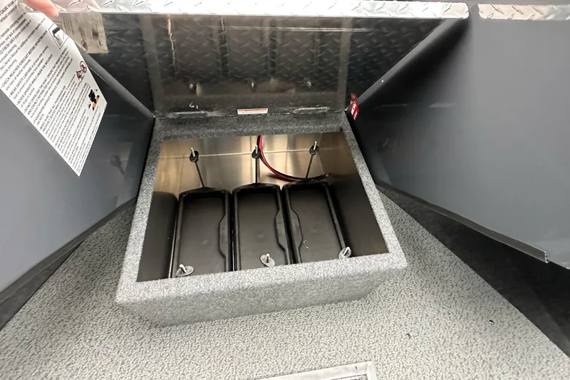 Slide: The Image of Open storage compartment in 2026 Lund 210 Heavy Gauge boat, featuring battery holders. - 27