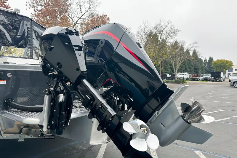 Slide: The Image of 2026 Lund 210 Heavy Gauge boat with dual outboard motors in a parking lot. - 5