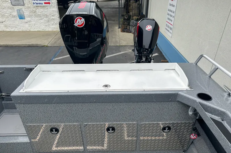 Slide: The Image of 2026 Lund 210 Heavy Gauge boat with dual Mercury outboard motors, docked near a service area. - 7