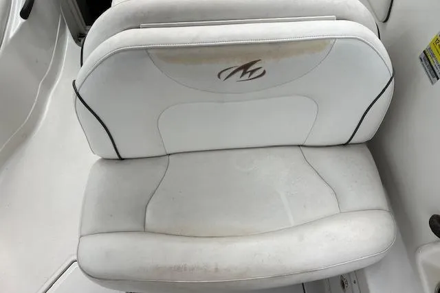 Slide: The Image of White seat on 2006 Monterey 250 Cruiser boat, featuring logo and slight wear. - 2
