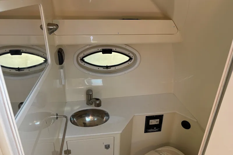 Slide: The Image of 2016 Monterey 295 Sport Yacht bathroom with sink, mirror, and oval window. - 25