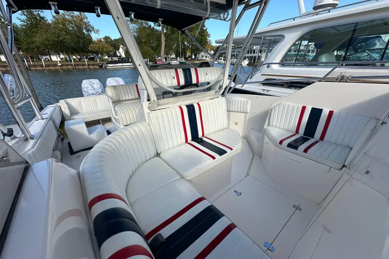 Slide: The Image of 1999 Intrepid 339 boat interior with white and striped seating, docked by the water. - 15
