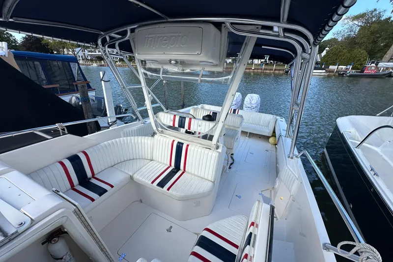 Slide: The Image of 1999 Intrepid 339 boat interior with striped seating, docked by the water. - 9