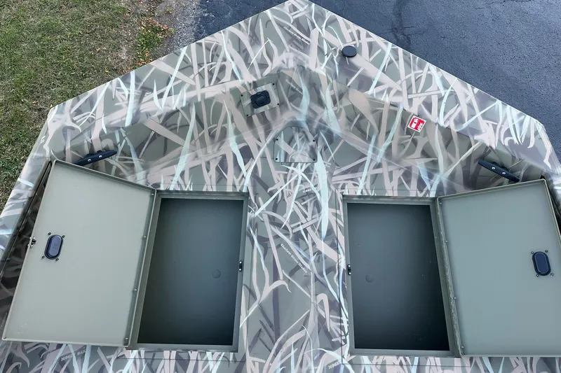 Slide: The Image of 2026 Lowe Roughneck 2070SC boat with open storage compartments and camouflage pattern. - 11