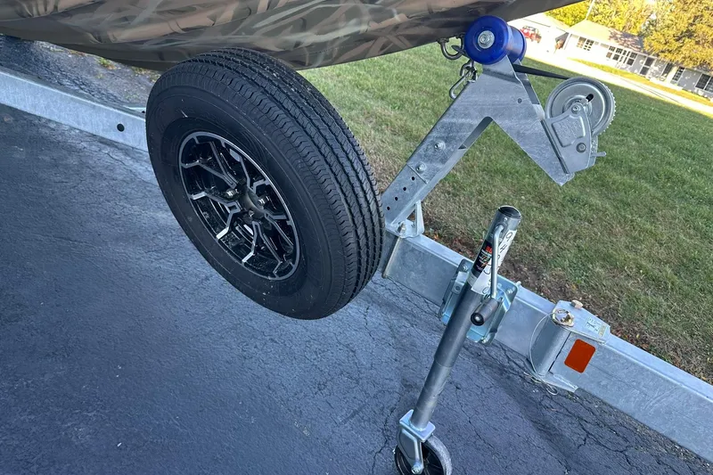 Slide: The Image of Trailer hitch and wheel of 2026 Lowe Roughneck 2070SC boat on pavement. - 23