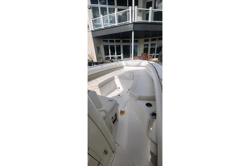 Slide: The Image of 2012 Boston Whaler 280 Outrage boat interior with seating, docked near modern building. - 18