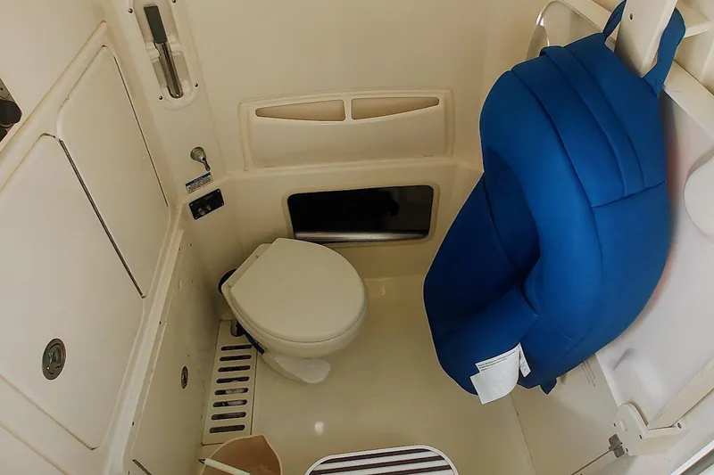 Slide: The Image of 2012 Boston Whaler 280 Outrage boat interior with toilet and blue seat cushion. - 41
