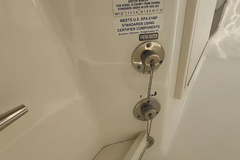Slide: The Image of 2012 Boston Whaler 280 Outrage fuel and water fill ports with EPA compliance label. - 48
