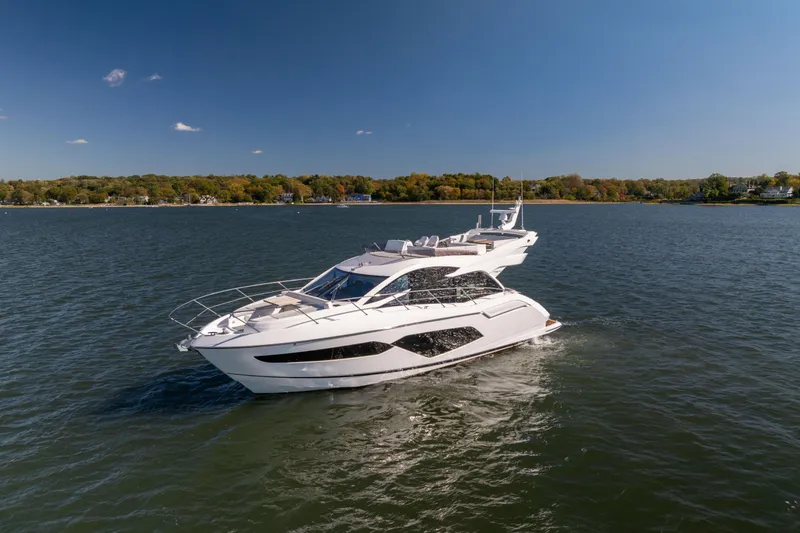 Slide: The Image of 2018 Sunseeker Manhattan 52 yacht cruising on a serene lake under a clear blue sky. - 10
