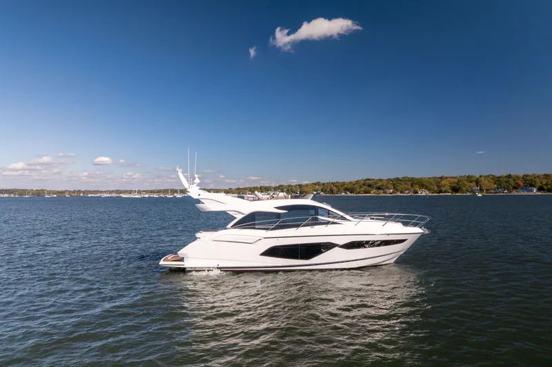 Slide: The Image of 2018 Sunseeker Manhattan 52 yacht cruising on a serene lake under a clear blue sky. - 3