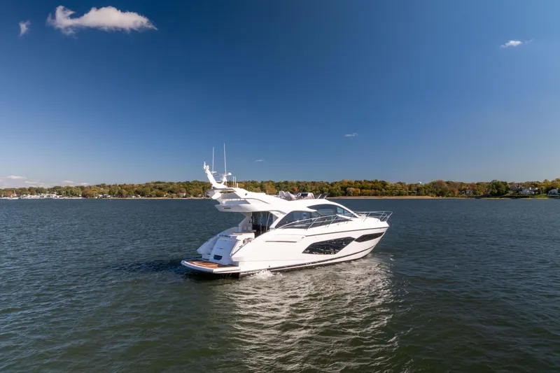 Slide: The Image of 2018 Sunseeker Manhattan 52 yacht cruising on a serene lake under a clear blue sky. - 5