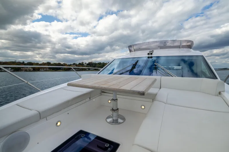 Slide: The Image of 2018 Sunseeker Manhattan 52 yacht deck with seating and table, under cloudy sky. - 62