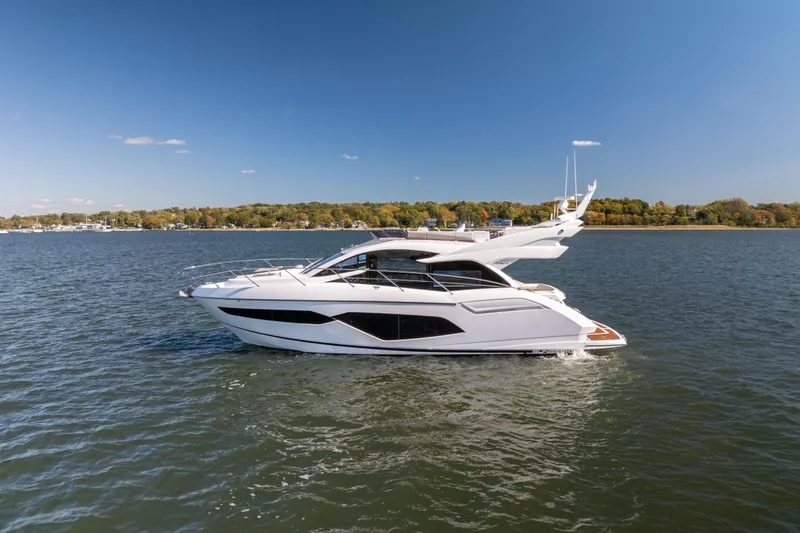 Slide: The Image of 2018 Sunseeker Manhattan 52 yacht cruising on a serene lake under a clear blue sky. - 9