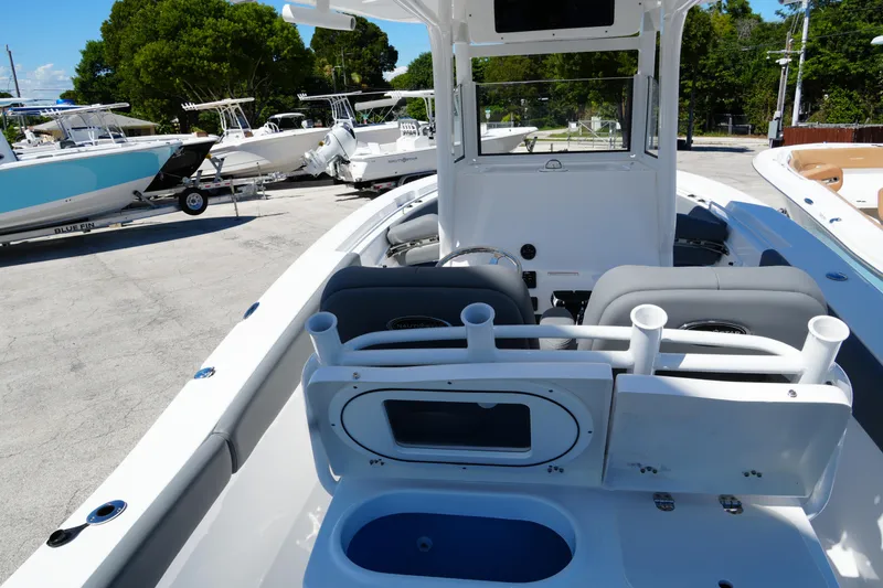 Slide: The Image of 2025 NauticStar 292 Legacy boat interior with seating and rod holders, parked outdoors. - 12