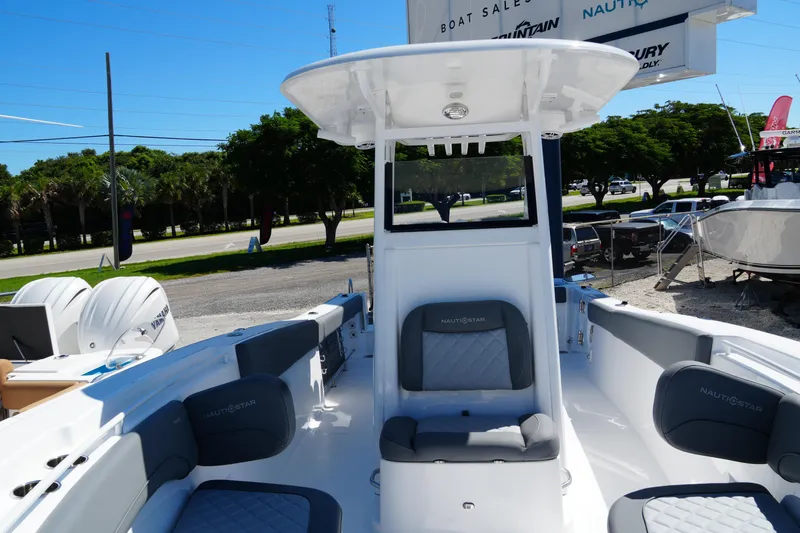 Slide: The Image of 2025 NauticStar 292 Legacy boat interior with seating and console, displayed outdoors. - 23