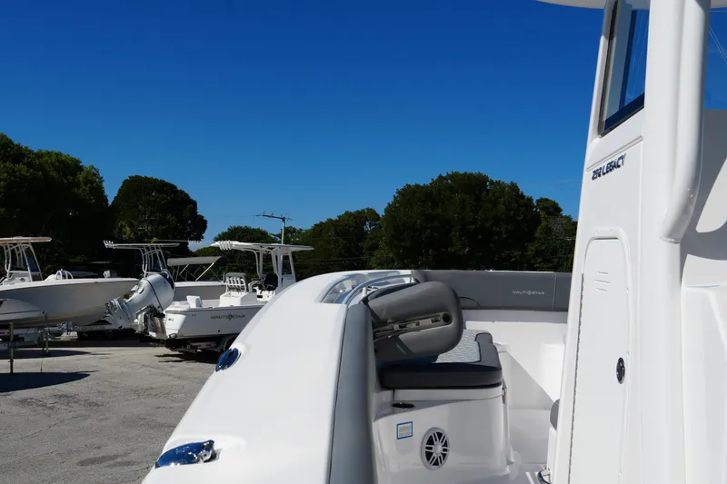 Slide: The Image of 2025 NauticStar 292 Legacy boat, sleek design, parked outdoors under clear blue sky. - 39