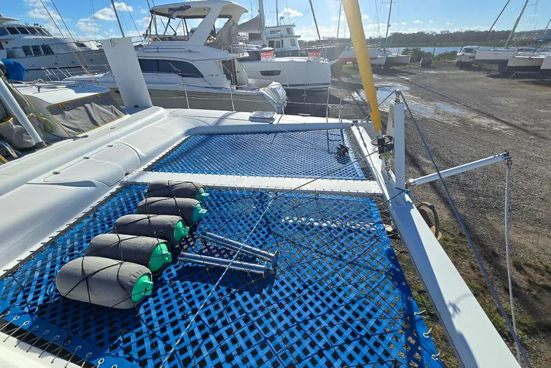 Slide: The Image of Catamaran deck with blue netting, fenders, and marina view; Dolphin 460, 2006 model. - 14