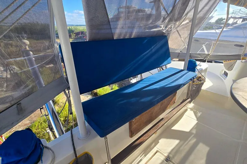 Slide: The Image of Blue cushioned seating on a 2006 Dolphin 460 catamaran deck, with protective canopy. - 23