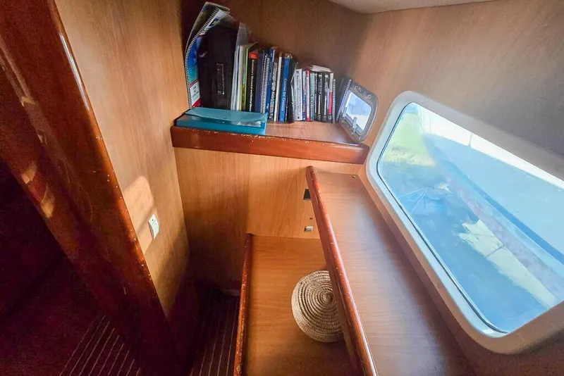 Slide: The Image of Cozy cabin interior of 2006 Dolphin 460 yacht with books and window view. - 38