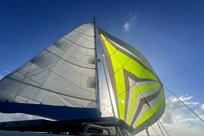Slide: The Image of Sailboat Dolphin 460 (2006) with vibrant sails against a clear blue sky. - 8