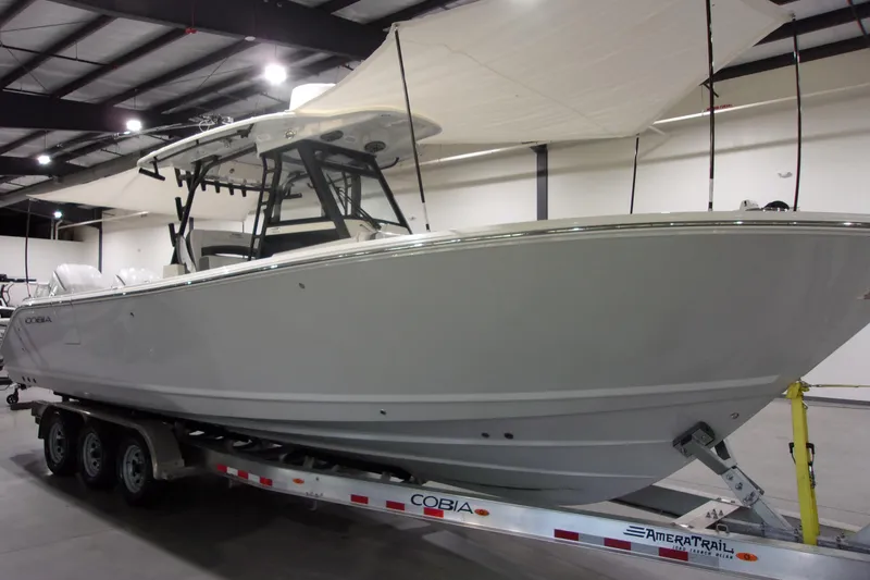 Slide: The Image of 2026 Cobia 305 Center Console boat on trailer in indoor showroom. - 3