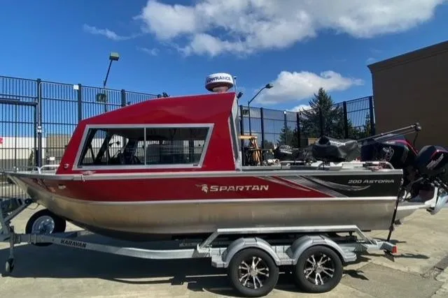 The Image of 2023 Spartan 200 Astoria boat on trailer, red and silver design, parked outdoors. - 0