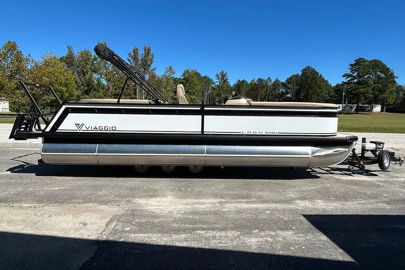 The Image of 2025 Viaggio Lago X-Q pontoon boat on trailer, parked outdoors under clear blue sky. - 1