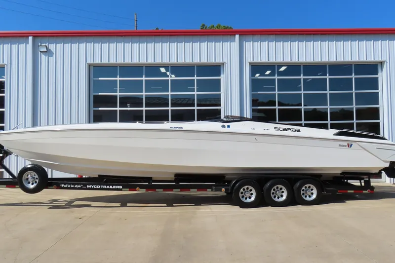 The Image of 1990 Wellcraft 38 Scarab boat on trailer, parked outside a modern building. - 0