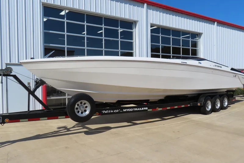 Slide: The Image of 1990 Wellcraft 38 Scarab boat on trailer outside a modern building. - 2
