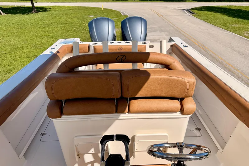 Slide: The Image of 2015 Sailfish 290 CC boat interior with brown leather seating and dual engines. - 14