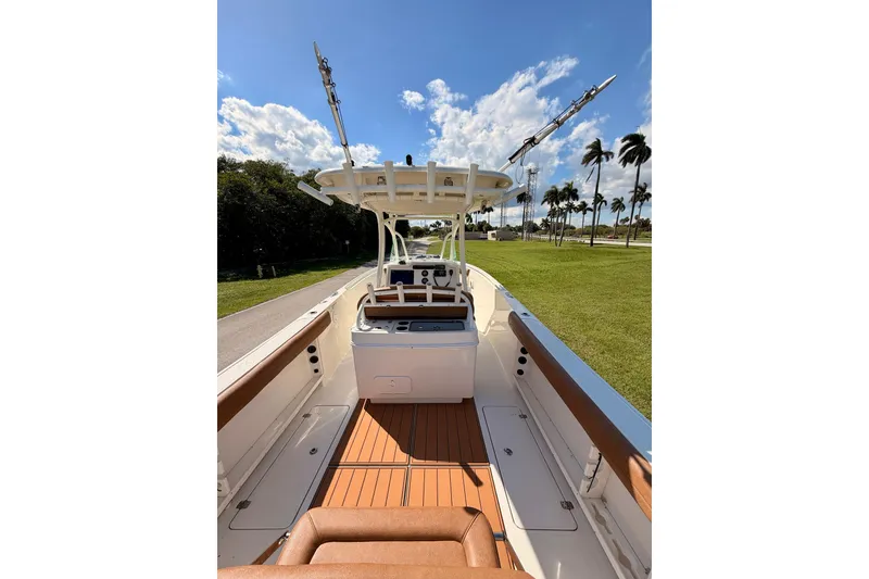 Slide: The Image of 2015 Sailfish 290 CC boat interior with brown seating, clear sky, and palm trees. - 23