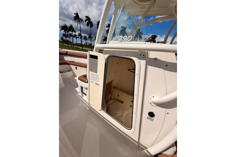 Slide: The Image of 2015 Sailfish 290 CC boat interior with open cabin door, palm trees in background. - 32