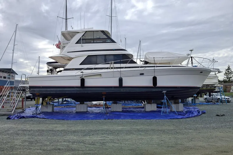 The Image of 2000 Riviera Enclosed Flybridge yacht docked in a marina, surrounded by other boats. - 0