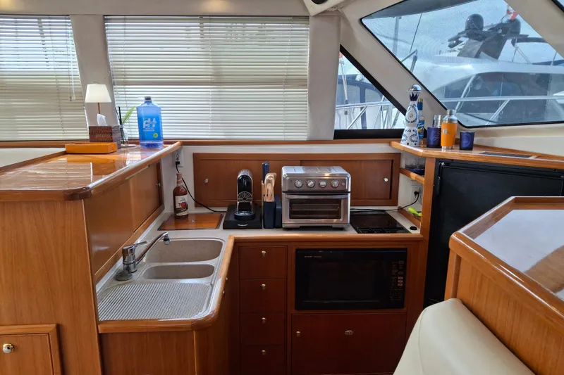 Slide: The Image of 2000 Riviera Enclosed Flybridge kitchen with modern appliances and wooden cabinetry. - 14