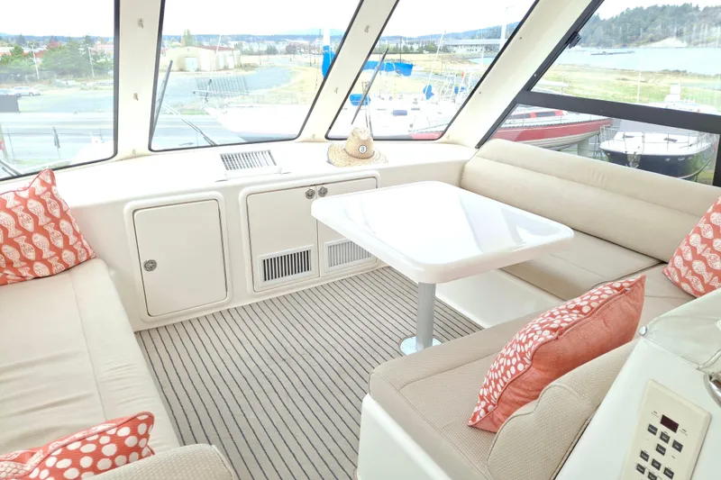 Slide: The Image of Interior of 2000 Riviera Enclosed Flybridge with beige seating and patterned cushions. - 37