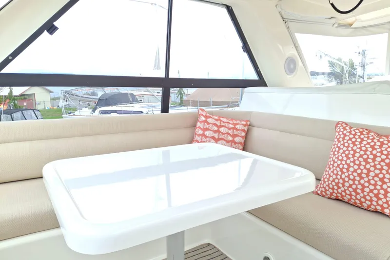 Slide: The Image of 2000 Riviera Enclosed Flybridge interior with seating, cushions, and marina view. - 38