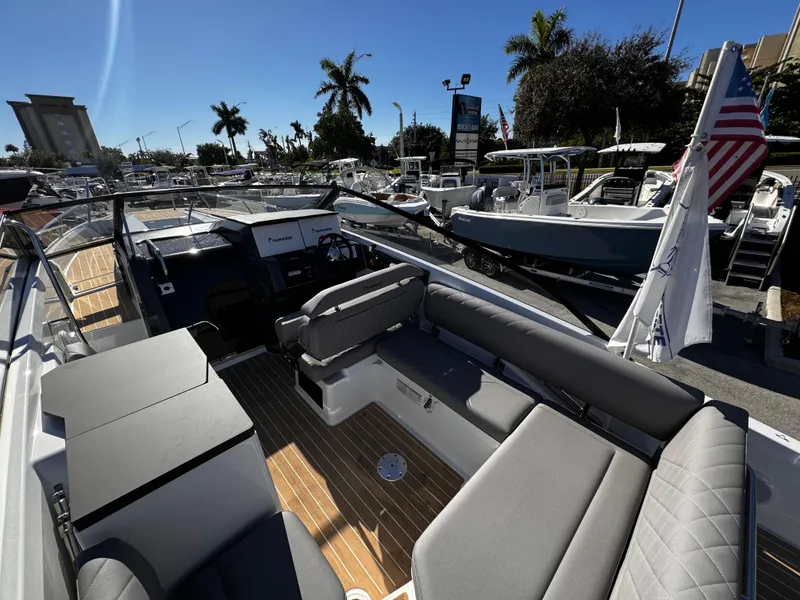 Slide: The Image of 2025 Yamarin 80DC boat interior with seating, docked under clear skies. - 2