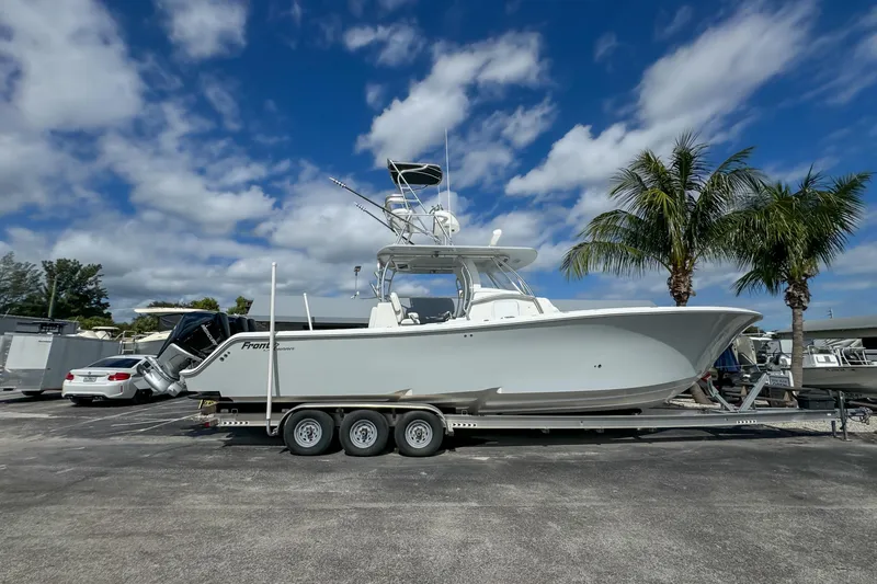 The Image of 2023 Front Runner 36 Center Console boat on trailer, parked under a blue sky with palm trees. - 0