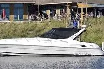 The Image of 2000 Wellcraft 45 Excalibur boat on stands, outdoors, with autumn trees in the background. - 0