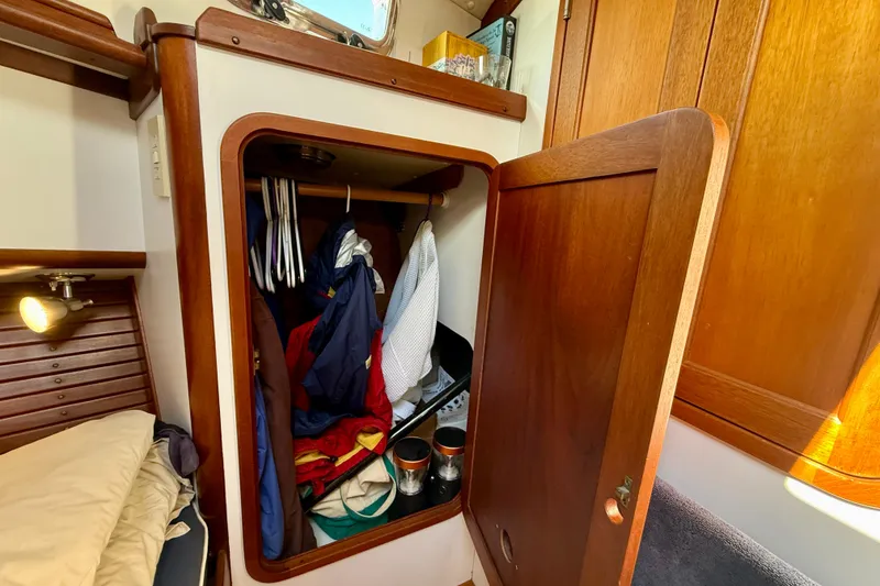 Slide: The Image of Wooden closet in 1999 Legacy 40 boat cabin, containing clothes and accessories. - 13