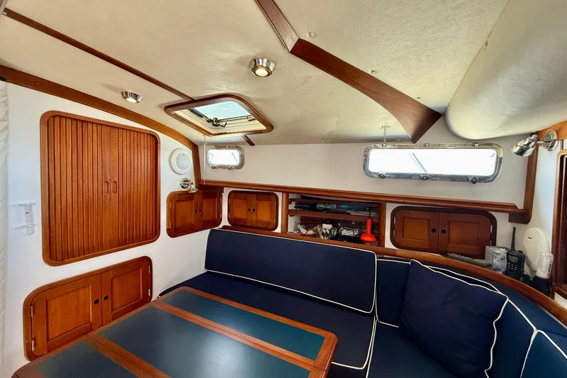 Slide: The Image of Cozy interior of 1999 Legacy 40 sailboat with wooden cabinets and navy seating. - 16