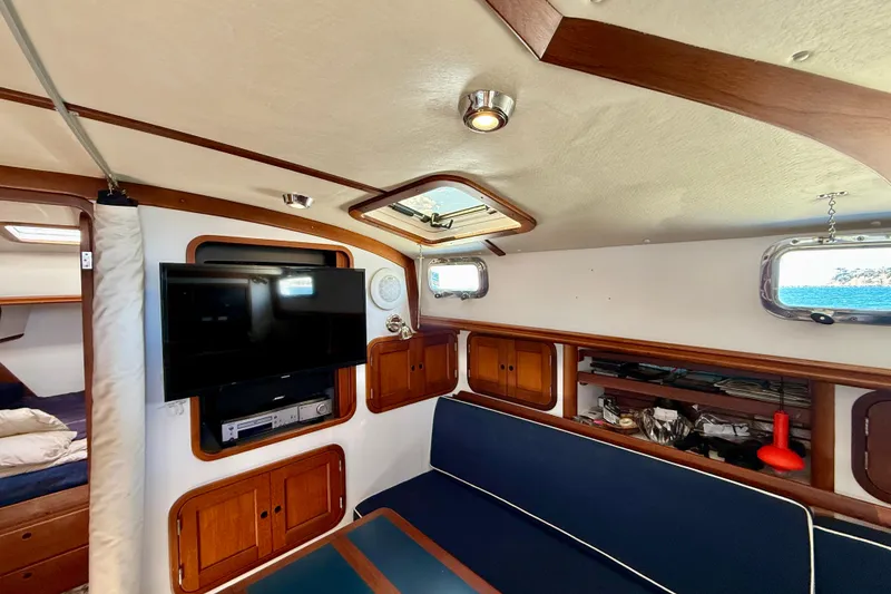 Slide: The Image of Interior of 1999 Legacy 40 yacht with TV, blue seating, and wooden cabinets. - 17