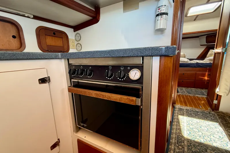 Slide: The Image of 1999 Legacy 40 yacht interior kitchen with oven, wooden cabinetry, and cozy bedroom view. - 21