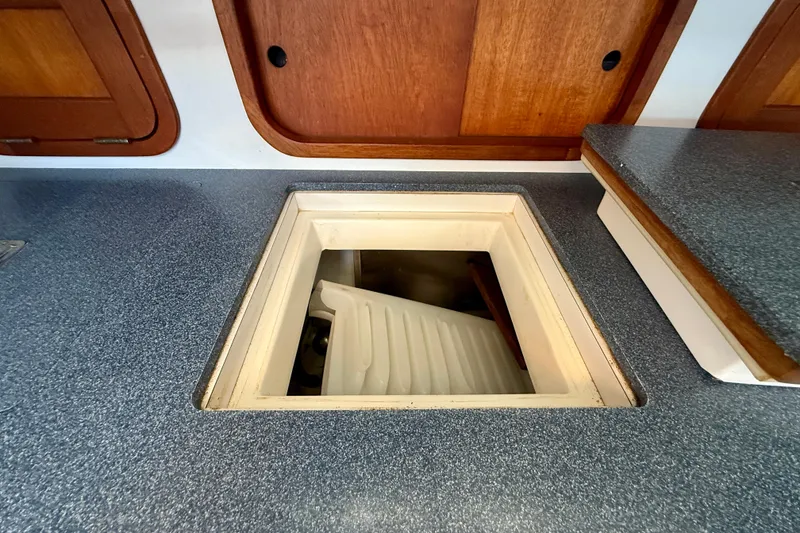 Slide: The Image of Boat interior with open hatch, revealing storage compartment, Legacy 40, 1999 model. - 23